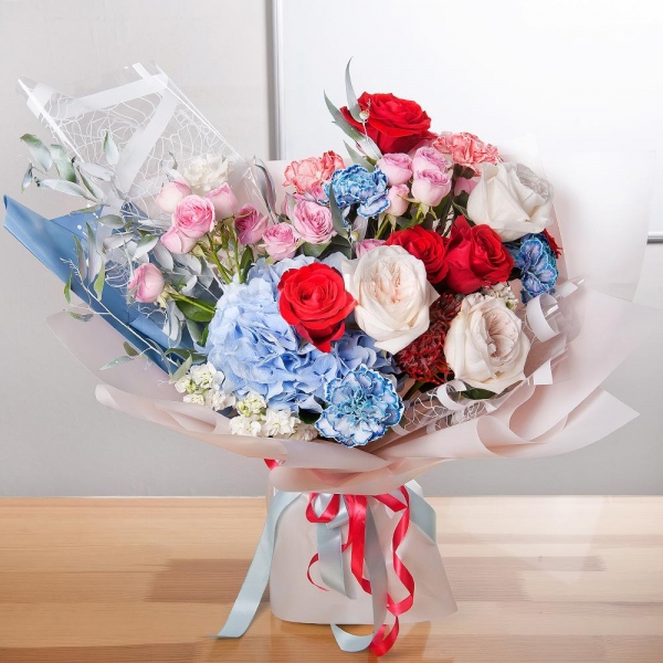 Bright pink spray rose mix, 50 cm - 3, Blue/purple hydrangea - 1, Blue carnation - 4, White Matthiola - 4, Red rose Nina 50 cm - 7, Peony style roses - 3, lisianthus - 1, Orange carnation - 4, Nutan, Ruscus italian, Wrapping Paper