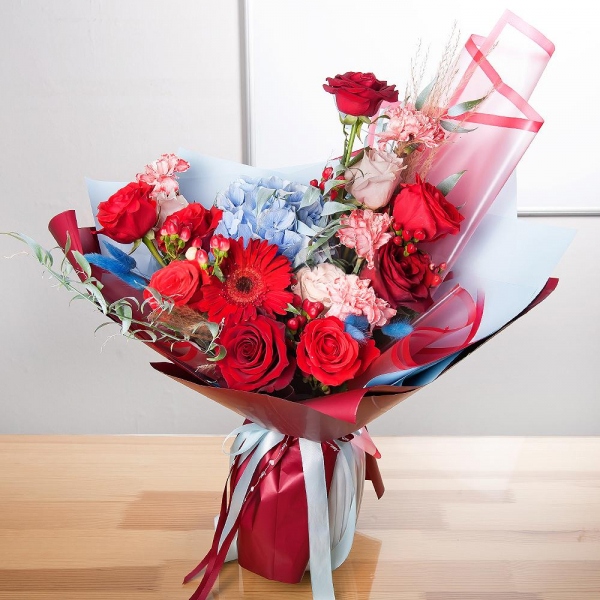 Gerbera red - 2, Blue/purple hydrangea - 1, Pink carnation - 9, Red rose 50 cm - 10, Rose Cream 50 cm - 5, Hypericum, Ruscus italian, Dried flowers in assortment, Wrapping Paper