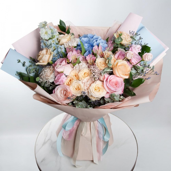 Blue/purple hydrangea - 1, Pink rose 50 cm - 5, Spray rose: white, cream, light pink 50 cm - 4, Rose Cream 50 cm - 6, Alstromeria white, soft pink - 5, Carnation white, cream - 9, Pink Lisianthus (Eustoma) - 3, Ozotamnus, Limonium (1 pc.), Blue Delphinium, Ruscus, Eucalyptus, Wrapping Paper